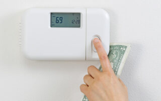 Closeup of a finger adjusting a thermostat.