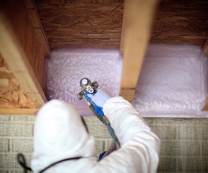 Worker installing insulation in basement rim joists and box sills.