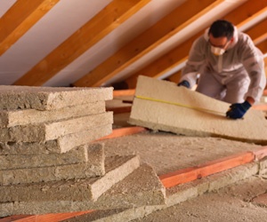 Worker installing mineral wool insulation in an attic.