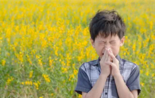 boy Suffering from Allergies in a field of yellow flowers