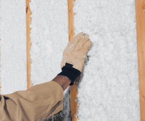 Worker's hand assessing wall insulation.