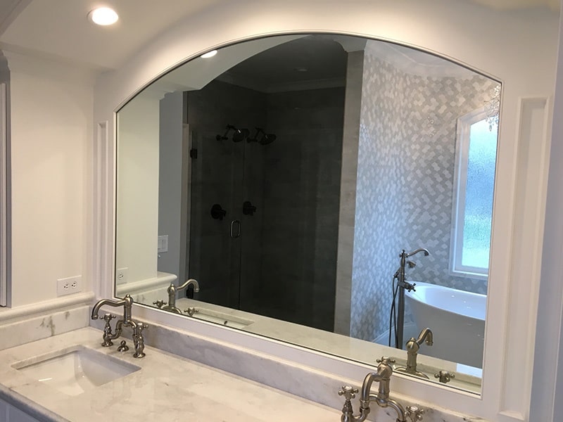 Custom shaped mirror above a bathroom vanity