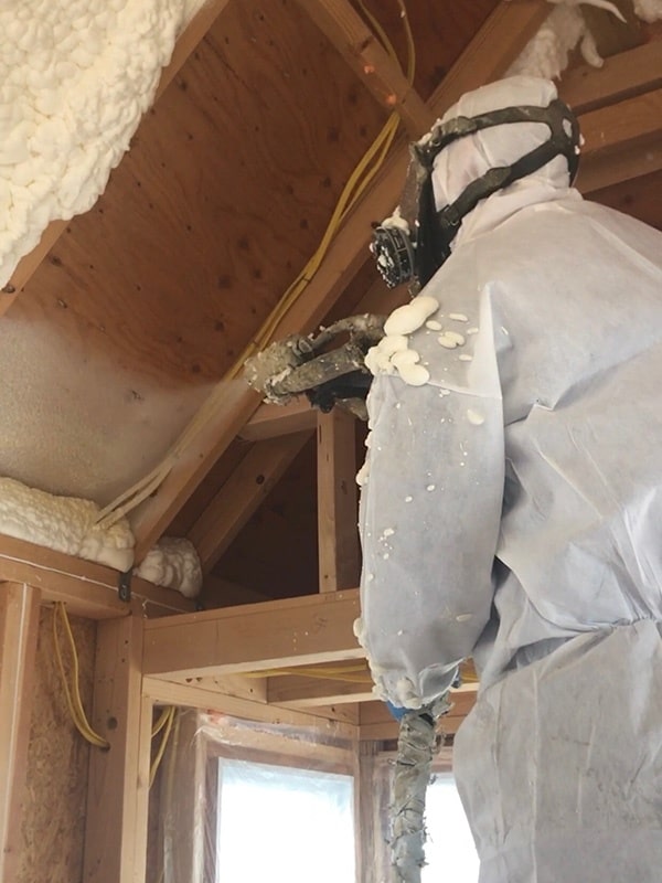Worker installing spray foam insulation