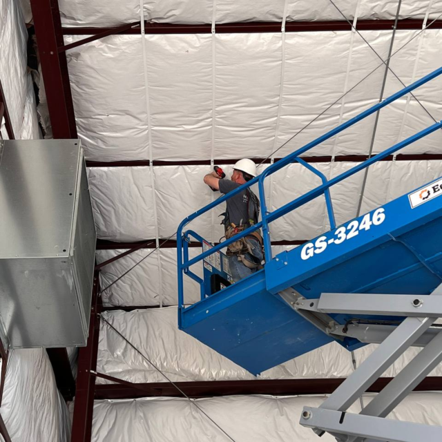 Worker putting up insulation on ceiling.
