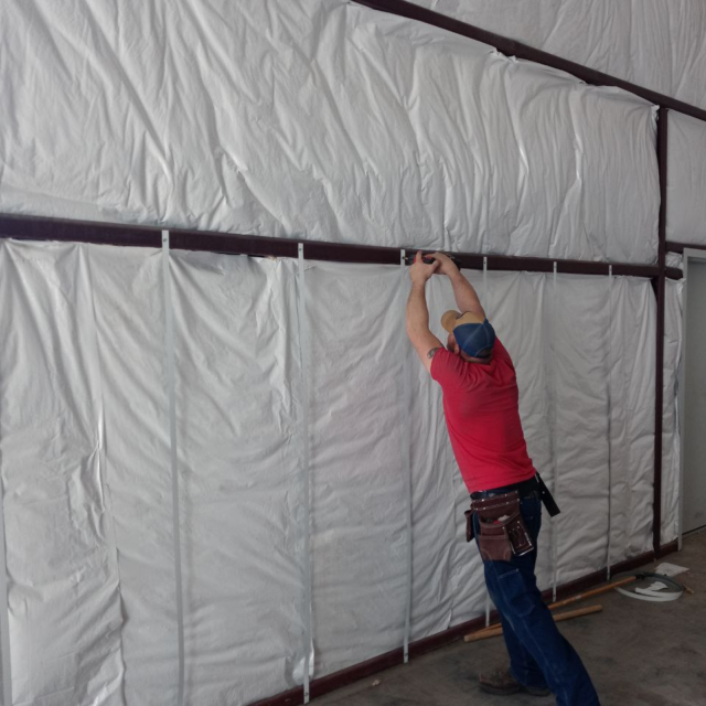 Man putting up insulation in commercial building.