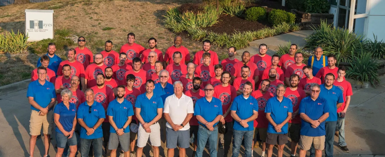 The Hayes Company Team standing outside wearing blue and red company shirts.
