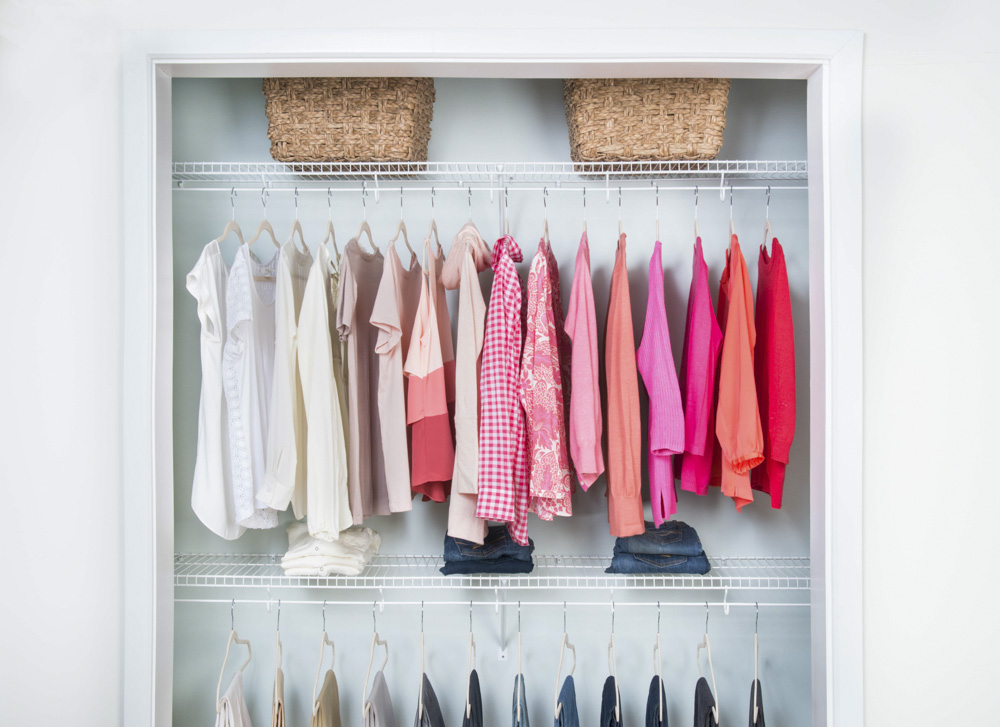 Brightly colored women's shirts hanging in on a white wire storage system in a closet
