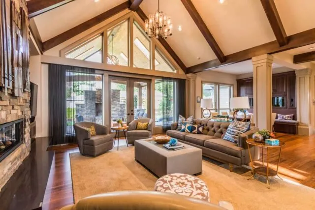Open living room and foyer with vaulted ceilings, wooden beams, and a modern chandelier.