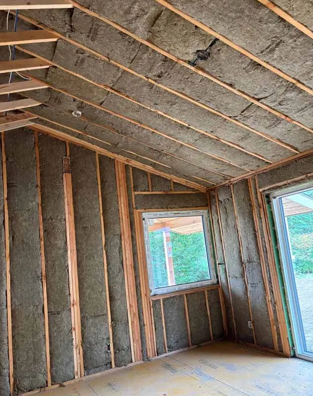 Framed residential interior with Rockwool mineral wool insulation installed in both walls and ceilings before drywall application.