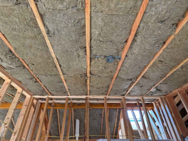 Ceiling view showing Rockwool mineral wool batts installed between joists for superior fire resistance and noise reduction.