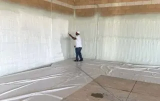 Close-up view of spray foam insulation equipment and hose setup on the floor during a commercial insulation project.