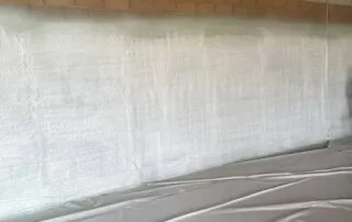 Insulation technician inspecting closed-cell spray foam application on commercial building walls for quality and consistency.