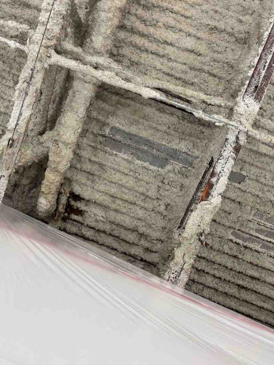Close-up of deteriorating existing insulation on a commercial natatorium ceiling deck.
