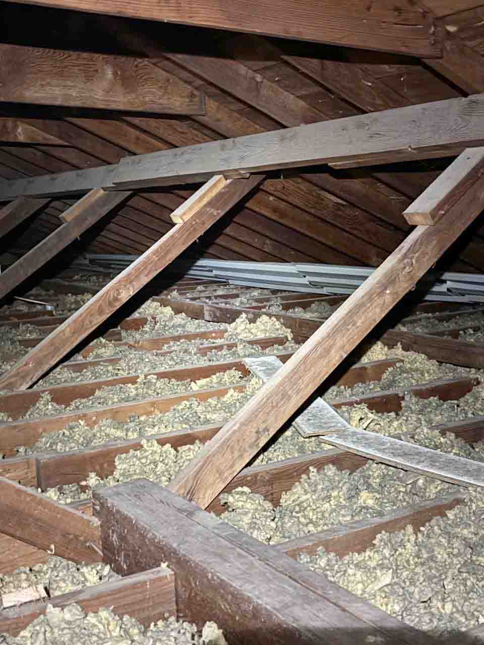 Blown-in fiberglass re-insulation added over attic floor between roof rafters.