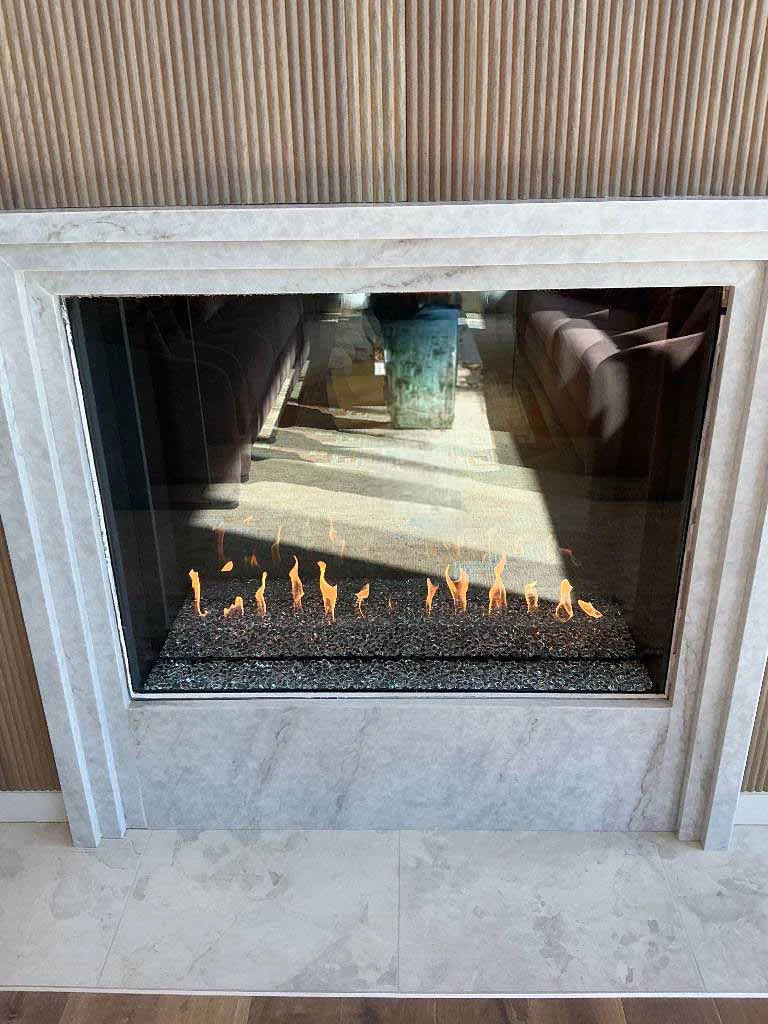 Finished Montigo Prodigy 2 gas fireplace with black fire glass media and a light stone surround at Berkley Riverfront in Kansas City, MO.