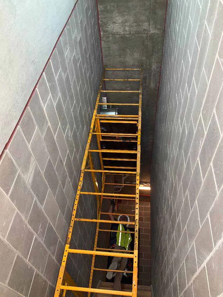 Hayes Company installer working from scaffolding inside a masonry vent chase for a Montigo Prodigy 2 gas fireplace at Berkley Riverfront in Kansas City, MO.