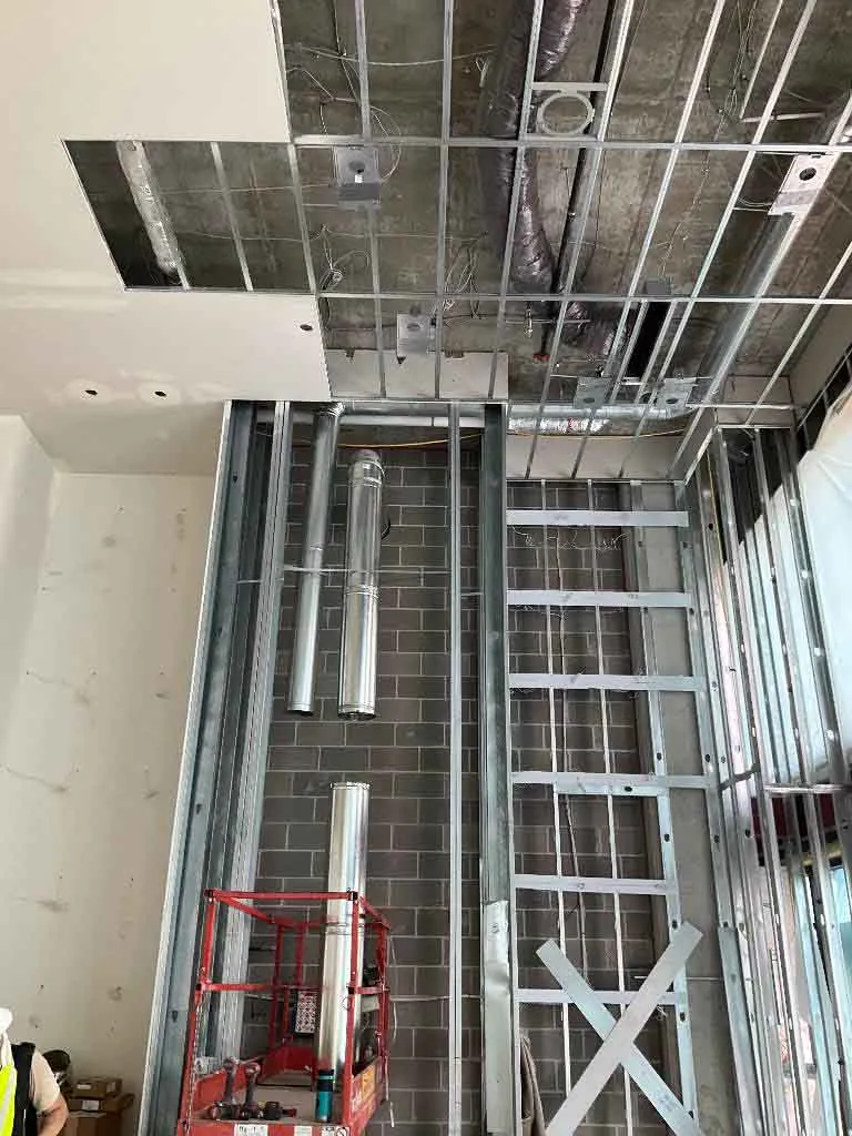 Hayes Company vent pipe sections staged against steel stud framing for a Montigo Prodigy 2 gas fireplace at Berkley Riverfront in Kansas City, MO.